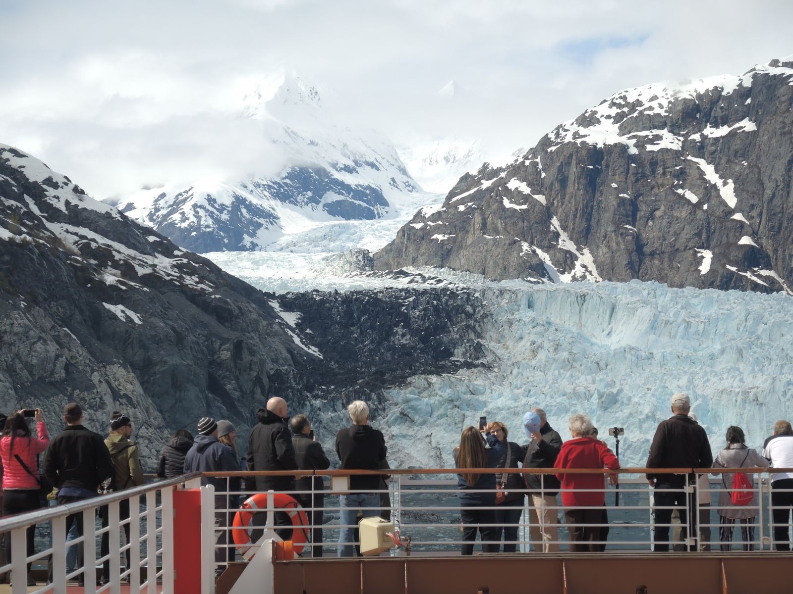 Passengers watching a glacier from a cruise ship deck in Alaska